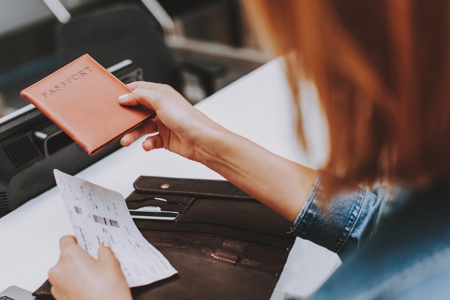 Female Passenger Holding Passport And Flight Ticket At Check In Counter