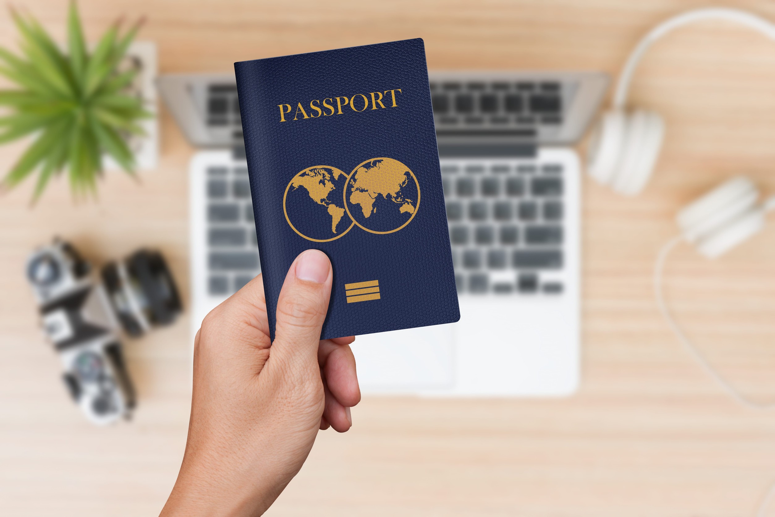 Hand Holding Blue Passport With Travel Stuffs Background
