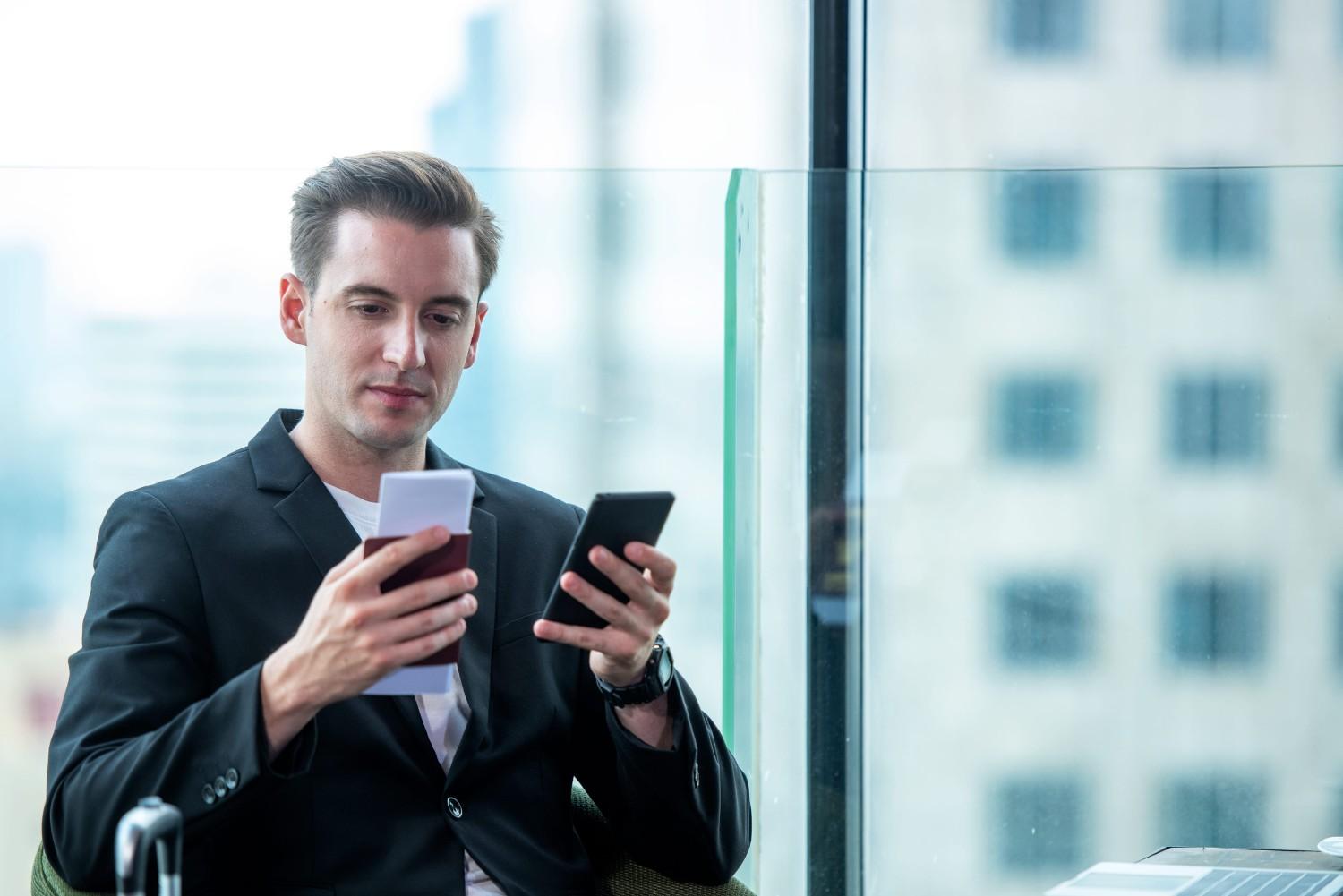 Man Holding Passport And Using Smartphone