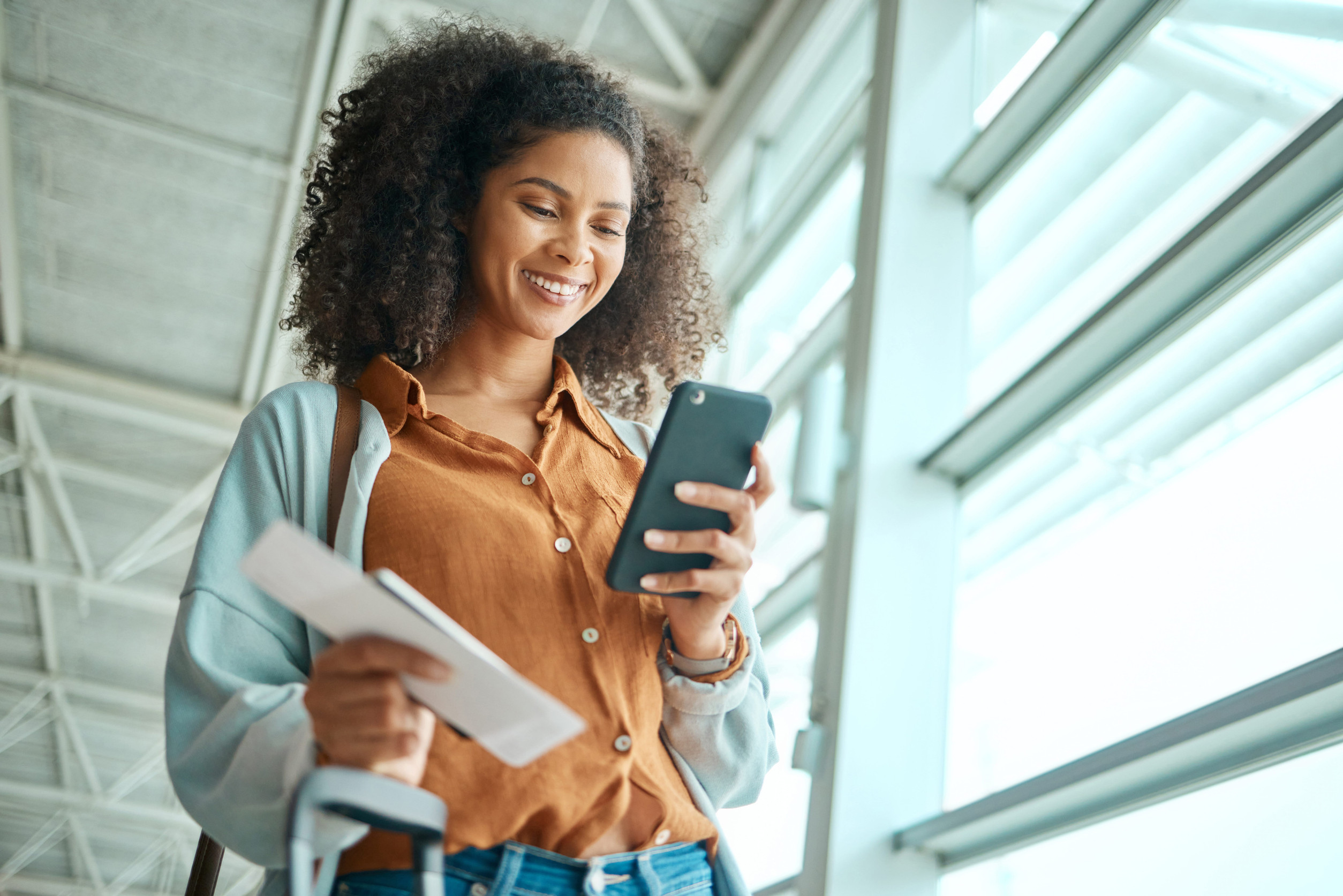 Tourist using phone and smiling at airport shop