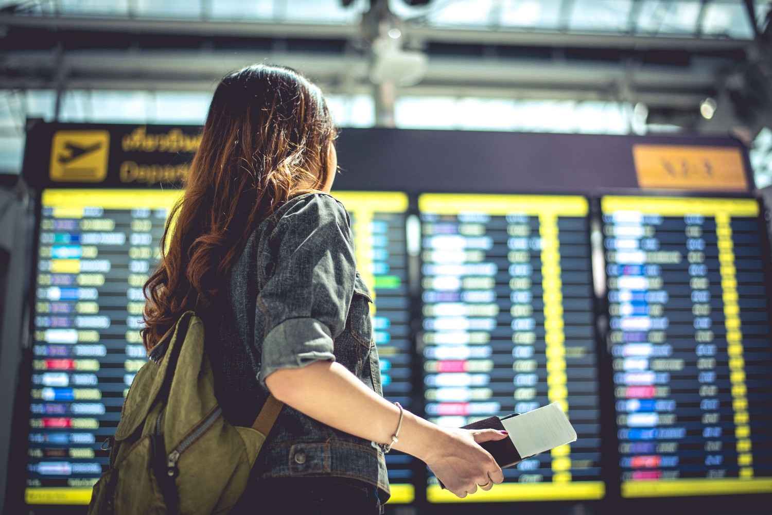 Woman Checking Flight Schedule At Airport Departure Board